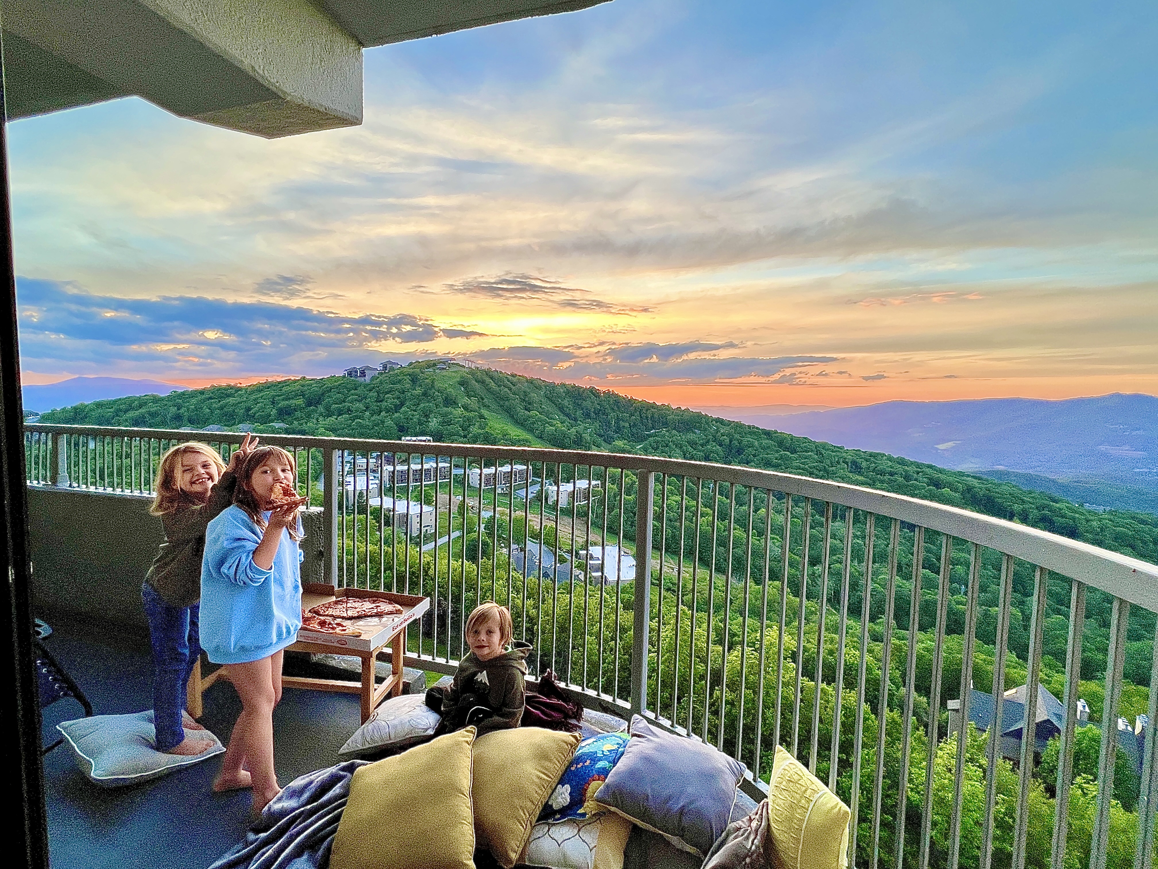 Kids on the balcony at sunset with pizza and pillows